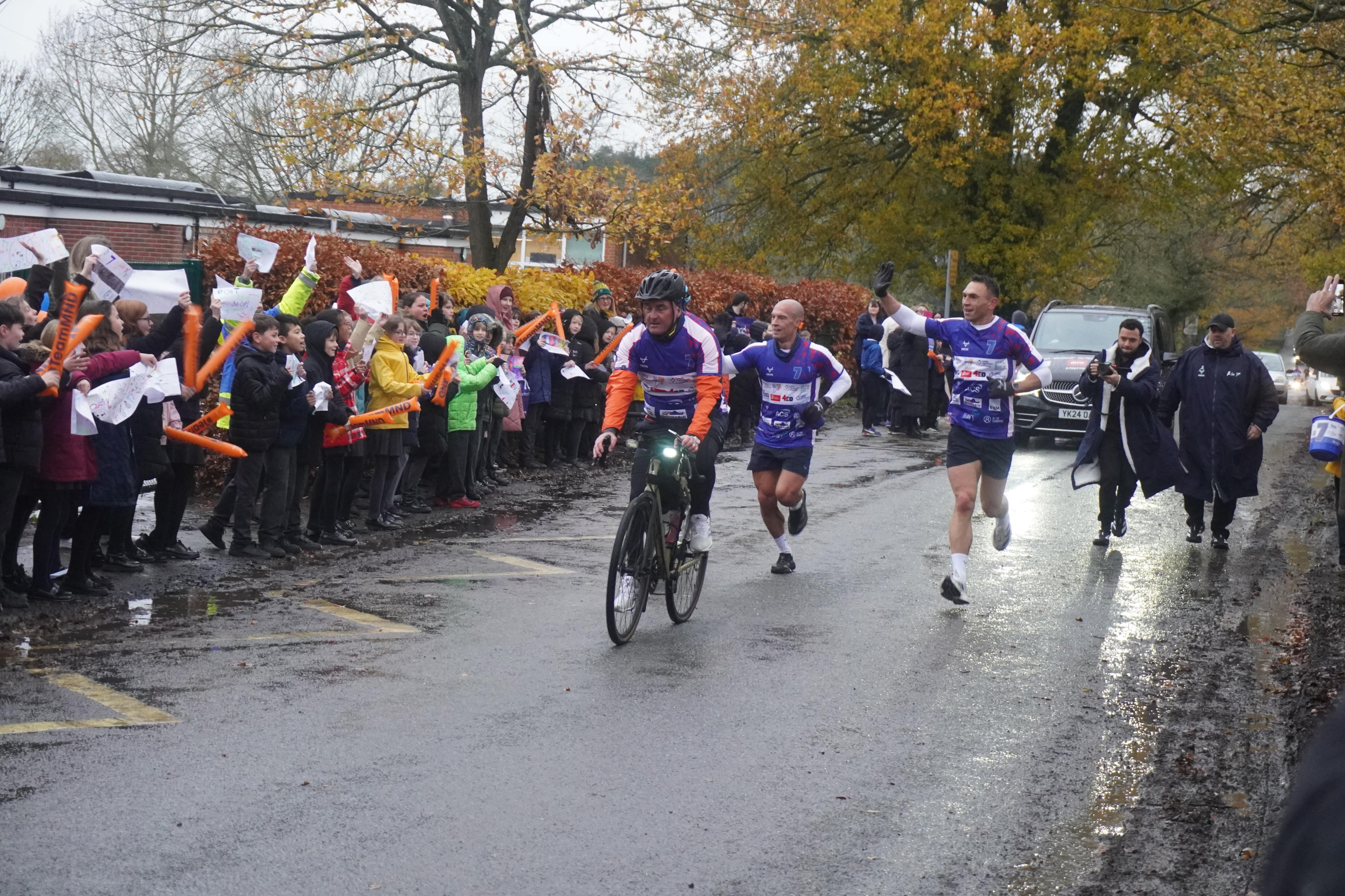 Kevin running in the rain with crowd cheering him on