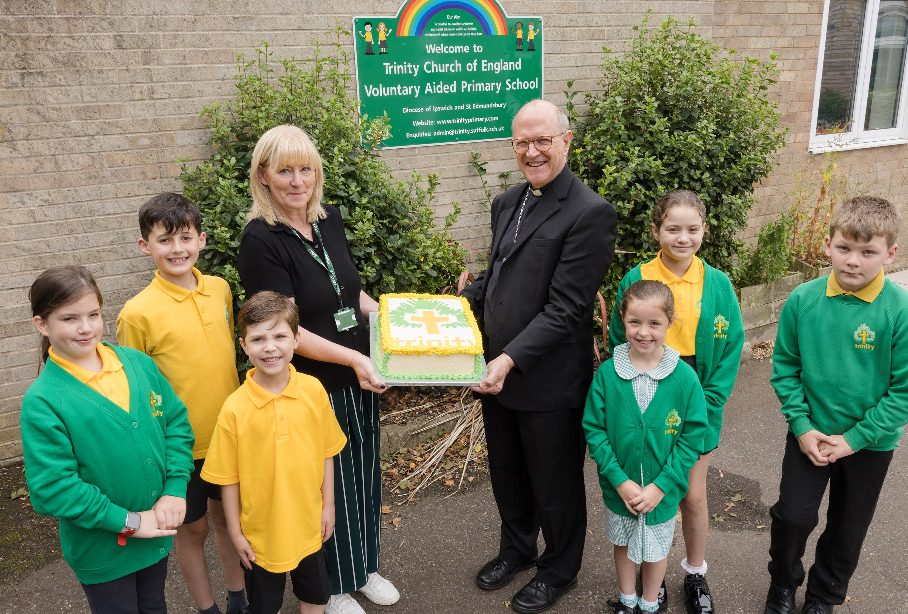 The Bishop of St Edmundsbury & Ipswich The Right Reverend Martin Seeley holding the 10th Anniversary cake with Linda Curran-Spain, the school’s head teacher,  and surrounded by some of the pupils at Trinity CEVAP School, Stowmarket. Photography by Keith Mindham.